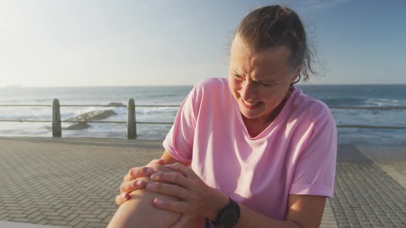 Senior woman in pain holding her leg on a promenade