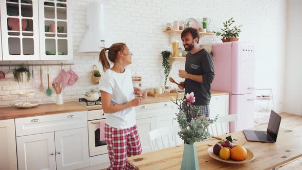 Happy Young Loving Couple Dancing in Kitchen Wearing Pajamas and Having Some Fun Slow Motion