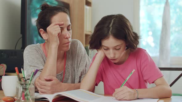 Mother helping her daughter to prepare homework at home