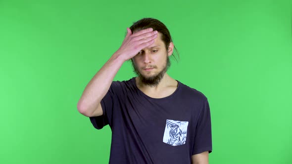 Portrait of a Young Man Suffering From Headache and Fatigue Puts His Hand to His Head