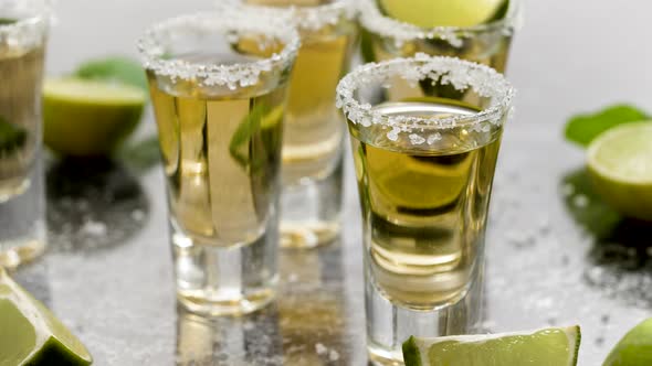 Golden Tequila Shots Served with Lime and Sea Salt on Table