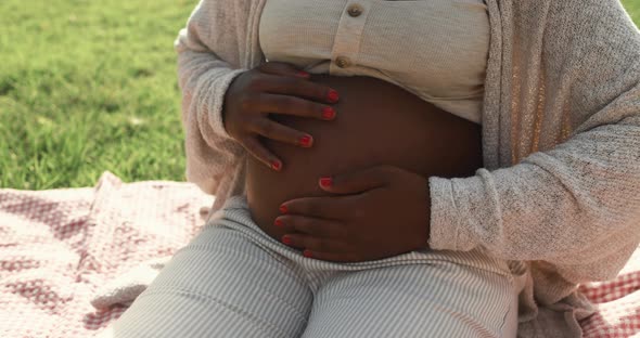 African pregnant woman holding her belly outdoor