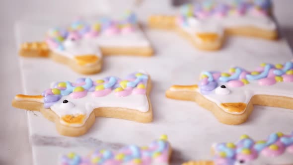 Step by step. Decorating unicorn shaped sugar cookies with royal icing for little girl birthday part