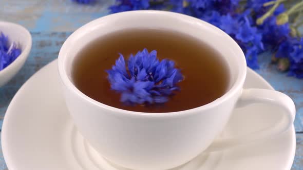 Brewing a tisanes from knapweeds flowers in white cup.