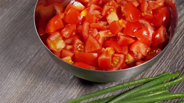 Freshly Cut Red Tomato in a Metal Bowl Next to Fresh Green Onions