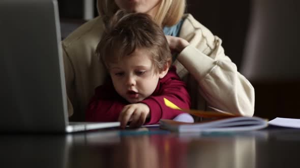 Little boy play with pencils while mother is working at home