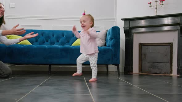 Little Baby Girl in Pink Making First Steps Toward Mother