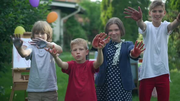 Four Positive Skilled Caucasian Children Laughing Waving with Colored Hands in Slow Motion Looking