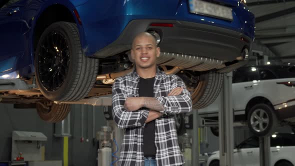 Happy Handsome Car Repairman Smiling to the Camera at His Garage