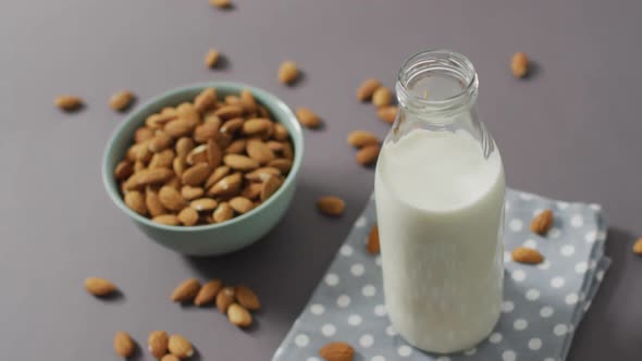 Video of fresh fruit almonds in a bowl and glass bottle of milk on grey background