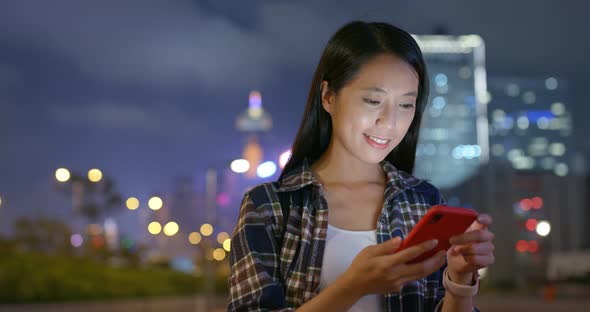 Woman work on mobile phone in city at night