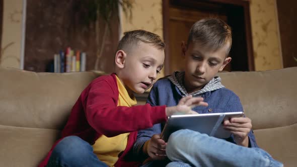 Schoolboys Sitting on Comfortable Sofa in Beautiful Room and Use Tablet PC to Play Online games