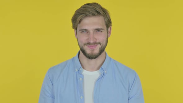 Approval By Young Man Shaking Head on Yellow Background