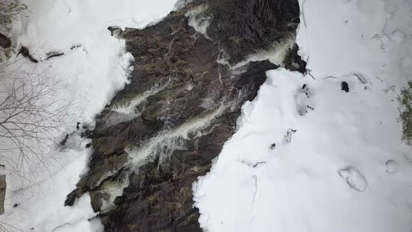 Drone shot going down on rapids on a snowy river