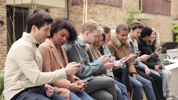 Multiracial group of friends with smartphones in the city