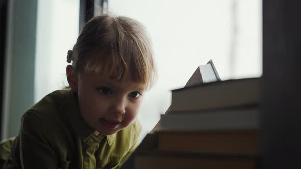 Cute Preschool Kid Girl Reads Book Lying Onwindow Sill Alone