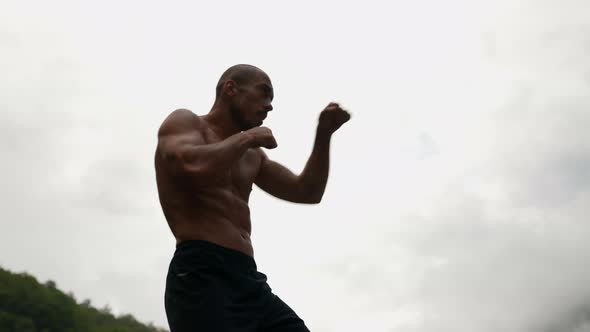 a Male Silhouette with a Bare Torso Against a Light Sky