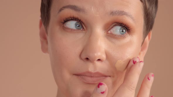 Caucasian Woman with Short Haircut and Natural Beige Makeup in Studio on Beige Background