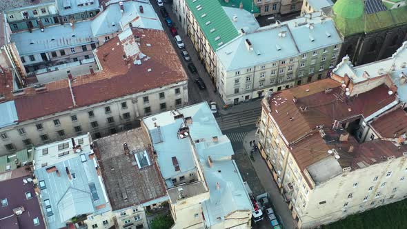 Aerial of European buildings and people walking the streets of Lviv Ukraine with cars parked on the