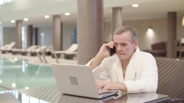 Old Businessman Having Phone Conversation in Swimming Pool