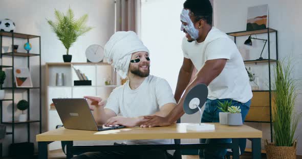 Young Men Watching Funny Videos on Computer while Applying cosmetic face procedures at home