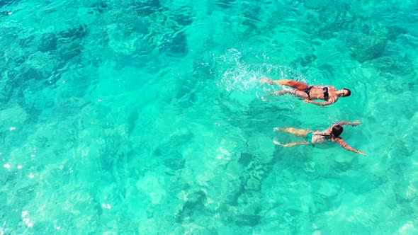 Aerial. two attractive women swimming in the azure water of the Caribbean sea. Splashing and having