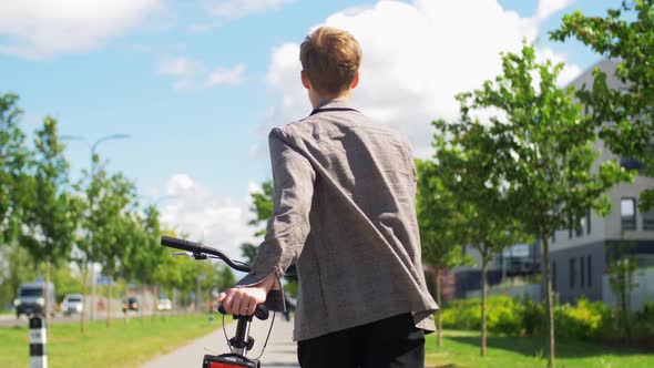 Young Man with Bicycle Walking Along City Street