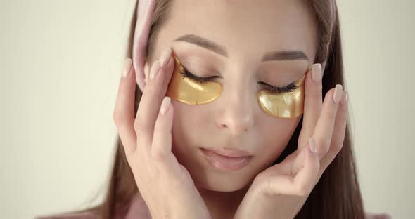 Woman Applying Hydrogel Undereye Recovery Patches on a Light Background