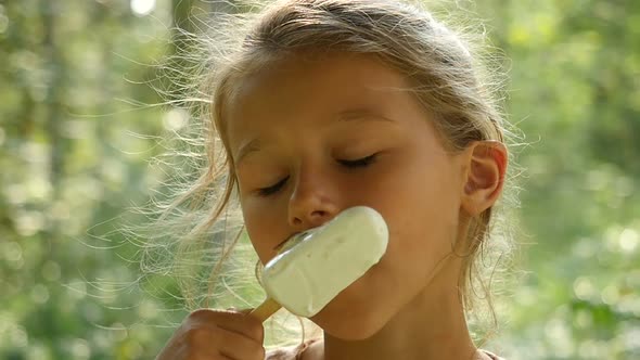 Kid Licking Ice-Cream. Charming Child Eats Ice Cream Outside. Little girl licking ice-cream.