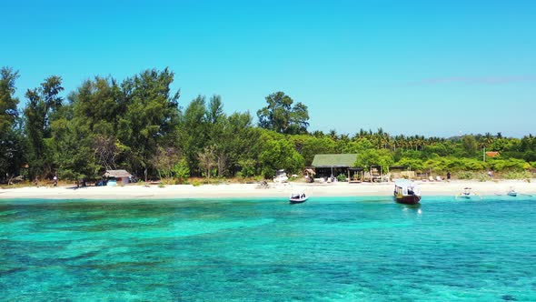 Quiet exotic beach with white sand bordered by green tropical trees and turquoise lagoon with clear