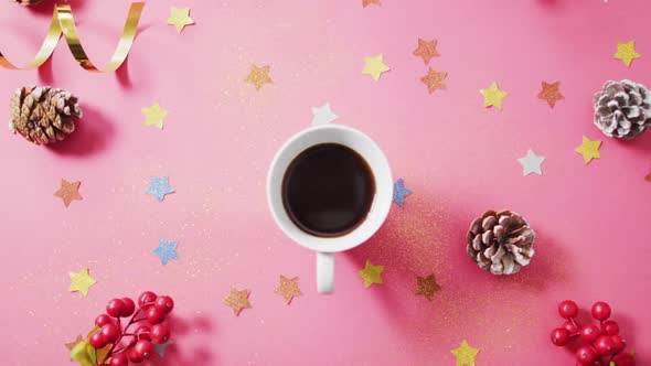 Video of coffee, red berries, stars and pine cones on pink background