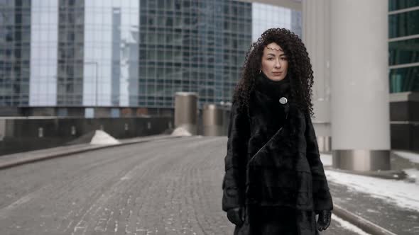 Luxury Brunette Woman Is Walking in City at Winter Looking at Camera Portrait