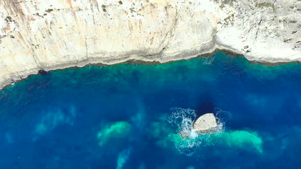 Drone shot over rocks and Cliffs with wave hitting a small rock in the Mediterranean sea of Malta 5