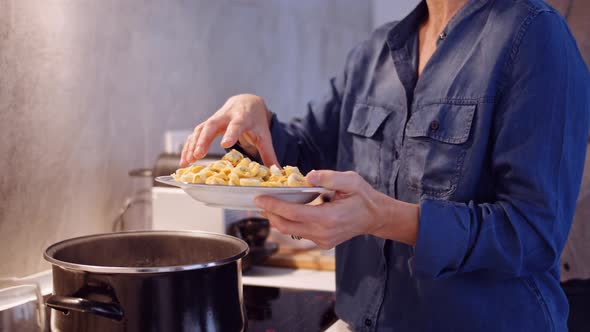 Slow motion shot of woman holding a plate with tortellini in kitchen