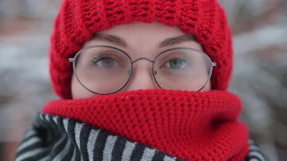 woman wearing a hat, scarf and glasses makes faces in the cold, glasses fog up