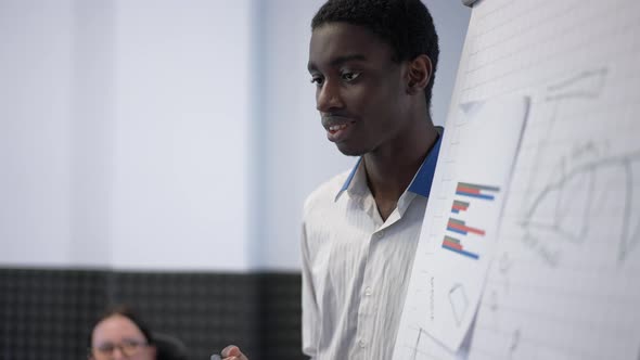 Confident Positive African American Man Talking with Colleagues in Office Explaining Annual