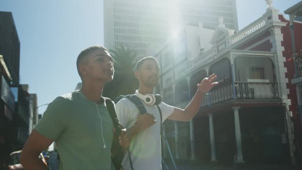 Two mixed race male friends standing, trying to catch cab in the street
