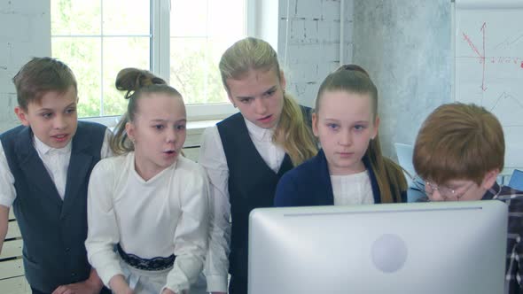 Little Businessmen Team Standing Near Table, Looking at Laptop