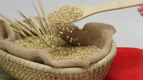 Falling Green Buckwheat From Wood Spoon Into Wicker Basket