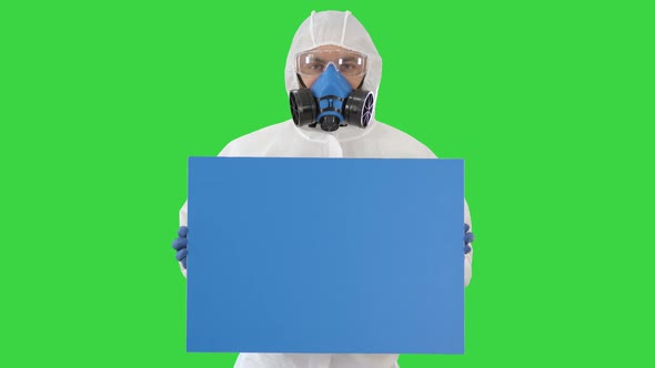 Male Doctor Wearing Protective Clothes Holding Blank Banner on a Green Screen, Chroma Key.