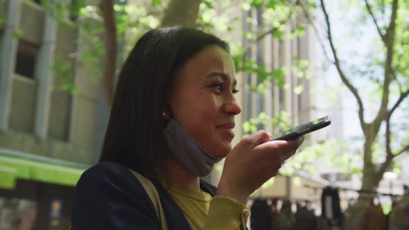 African american woman wearing face mask talking on smartphone