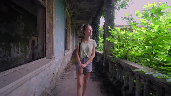 Young beautiful tourist woman walks through abandoned building