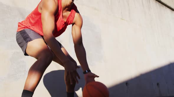 Fit african american man exercising outdoors in city, bouncing basketball