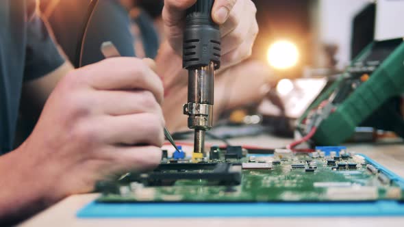 Worker Desoldering System Board Components Using Heat Gun Tweezers