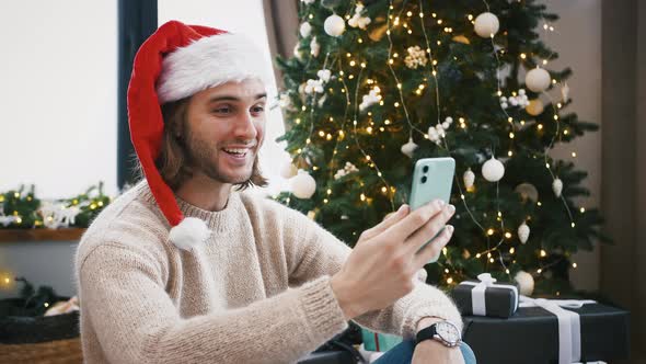 Man Smiling Greeting Someone Happy New Year and Cheering with Champagne By Video Call on Smartphone