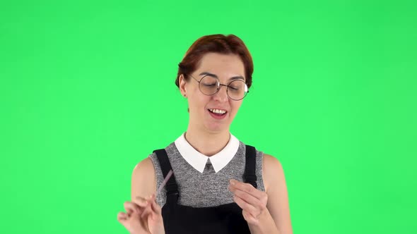 Portrait of Funny Girl in Round Glasses Is Making Herself Manicure with Pink Nail File. Green Screen