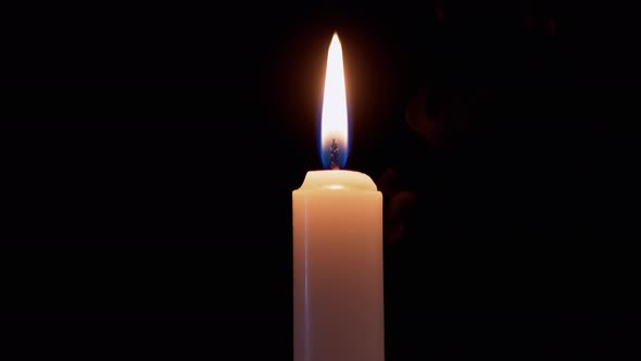 White Paraffin Candle Burns with a Calm Even Fire Flame on Black Background