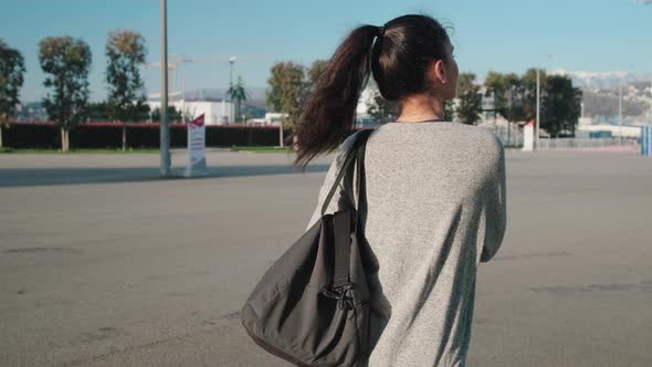 Young Woman with Gym Bag Walking in the Street