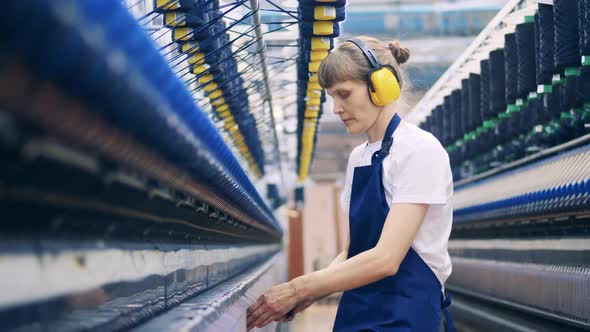 Female Worker is Taking Extra Threads Out of the Machinery