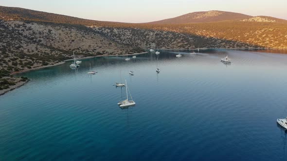 Catamaran and Sail Yachts Anchored at Bay on Deep Blue Sea Water on Sunrise